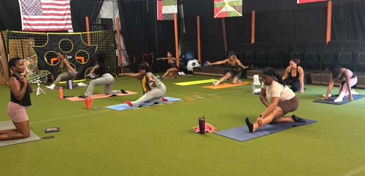 FitSquad participants stretching together on mats during an indoor yoga class